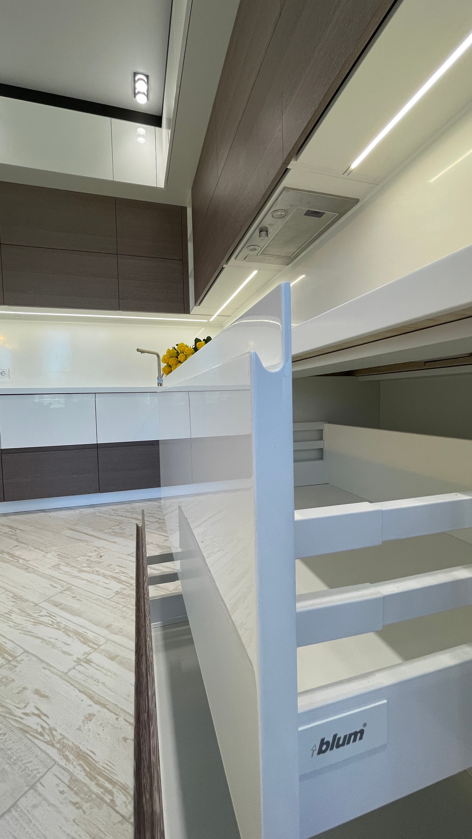 Крупный план выдвижного ящика Blum на фоне белой кухни с тёмным верхом
