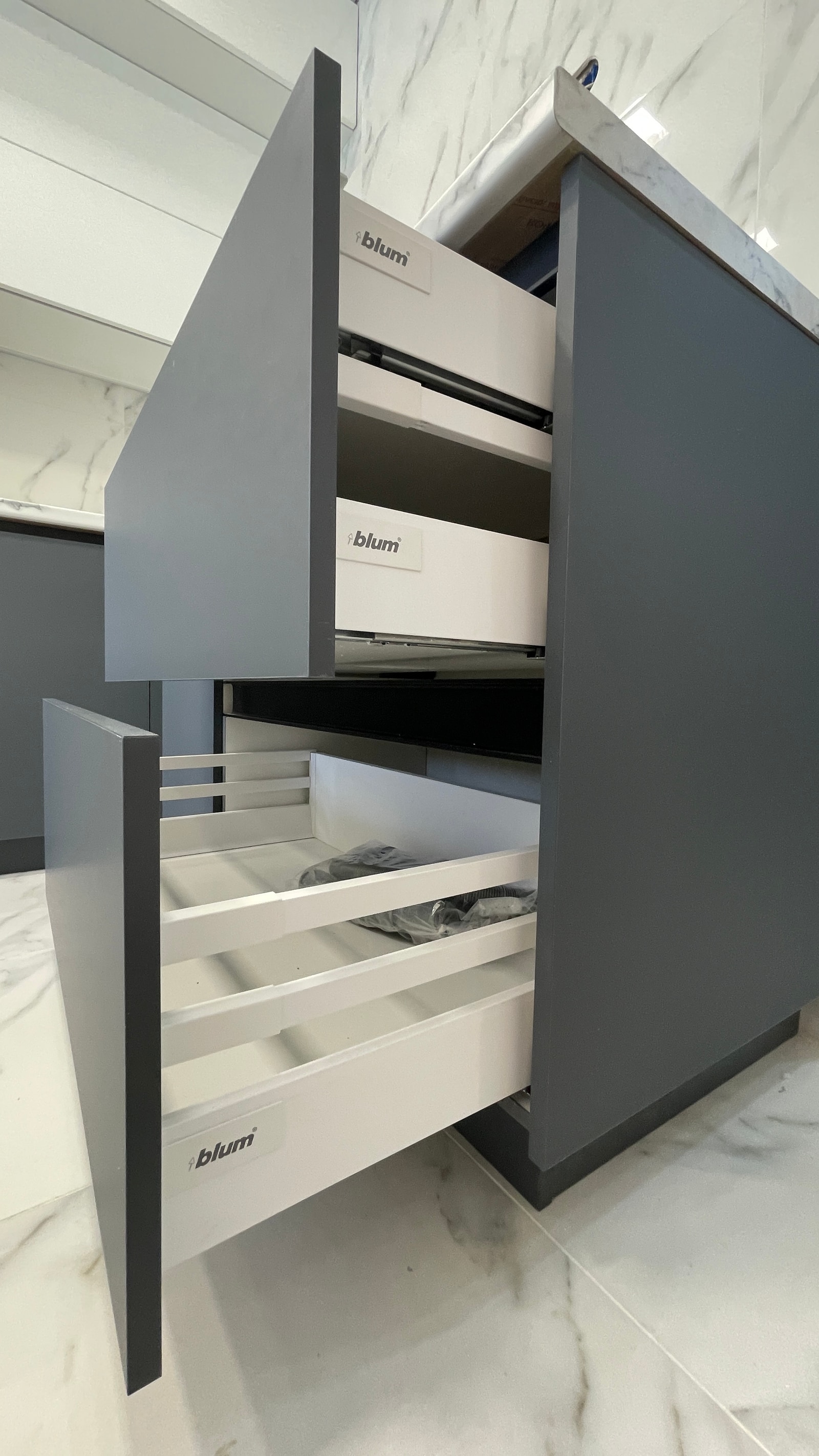 Крупный план трёх открытых выдвижных ящиков Blum в графитовом нижнем шкафу с органайзером для приборов